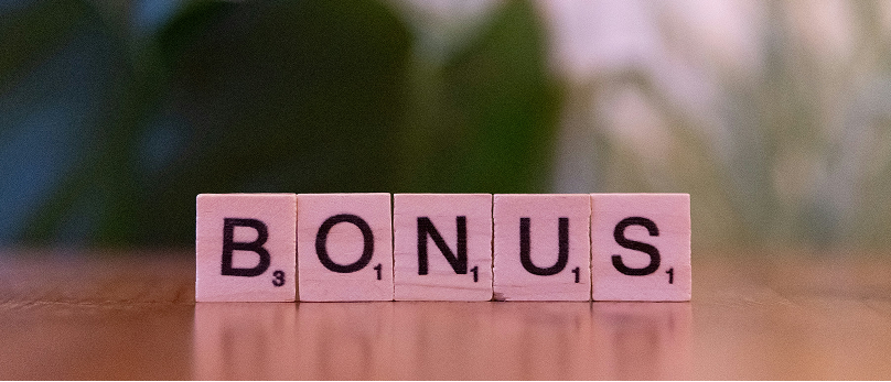 Wooden letter tiles spelling the word BONUS on a table.