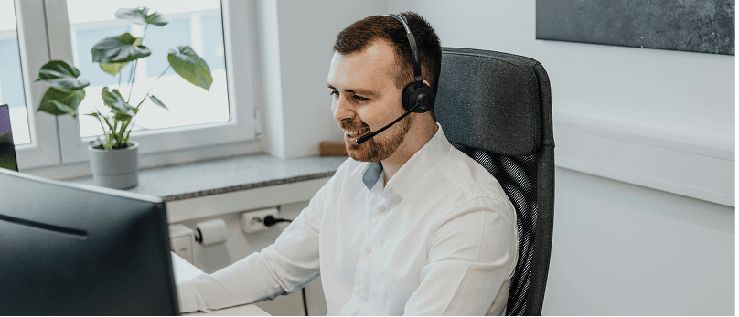 Person, die ein Headset trägt und an einem Computer in einem Büro arbeitet.