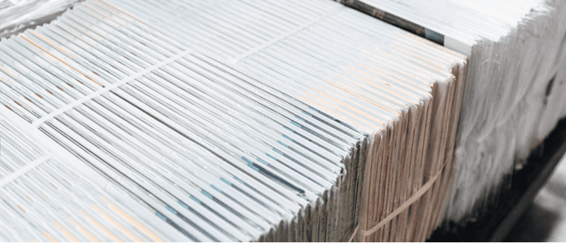 Stapel von gebündelten Zeitungen oder Zeitschriften, die in Reihen angeordnet sind.