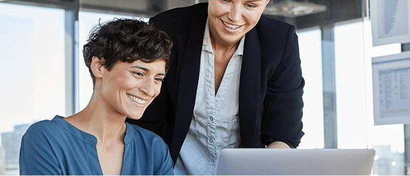 Zwei Kollegen arbeiten gemeinsam an einem Laptop.