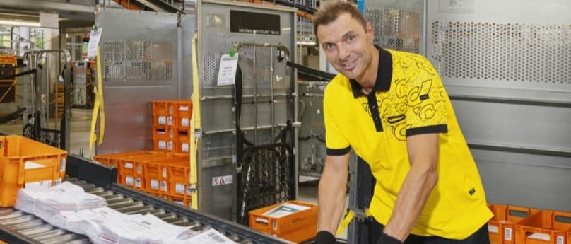 A worker organising packages on a conveyor belt in a logistics facility.